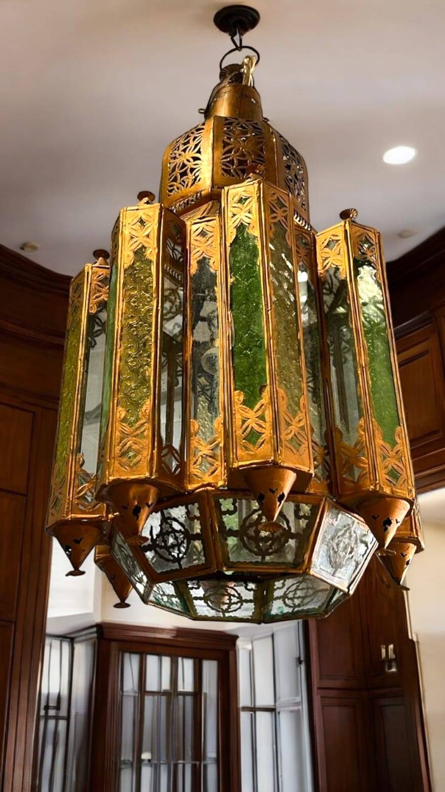 Farol musulmán colgante de metal dorado con paneles de cristal verde, ideal para decoración de interiores con estilo árabe en cocinas o salones.