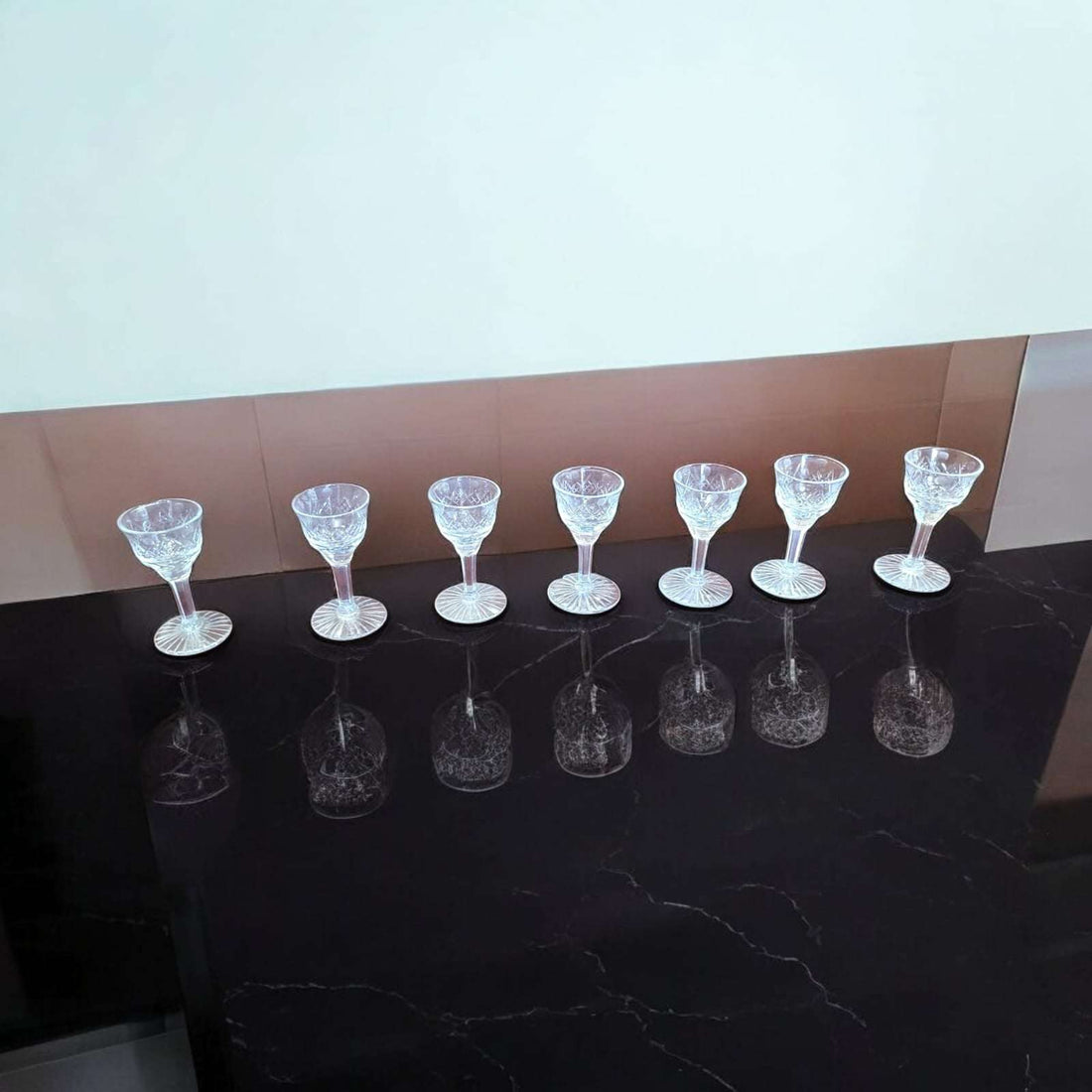 Juego de copas de licor de cristal tallado antiguo sobre mesa de mármol oscuro, diseño clásico ideal para decoración vintage.