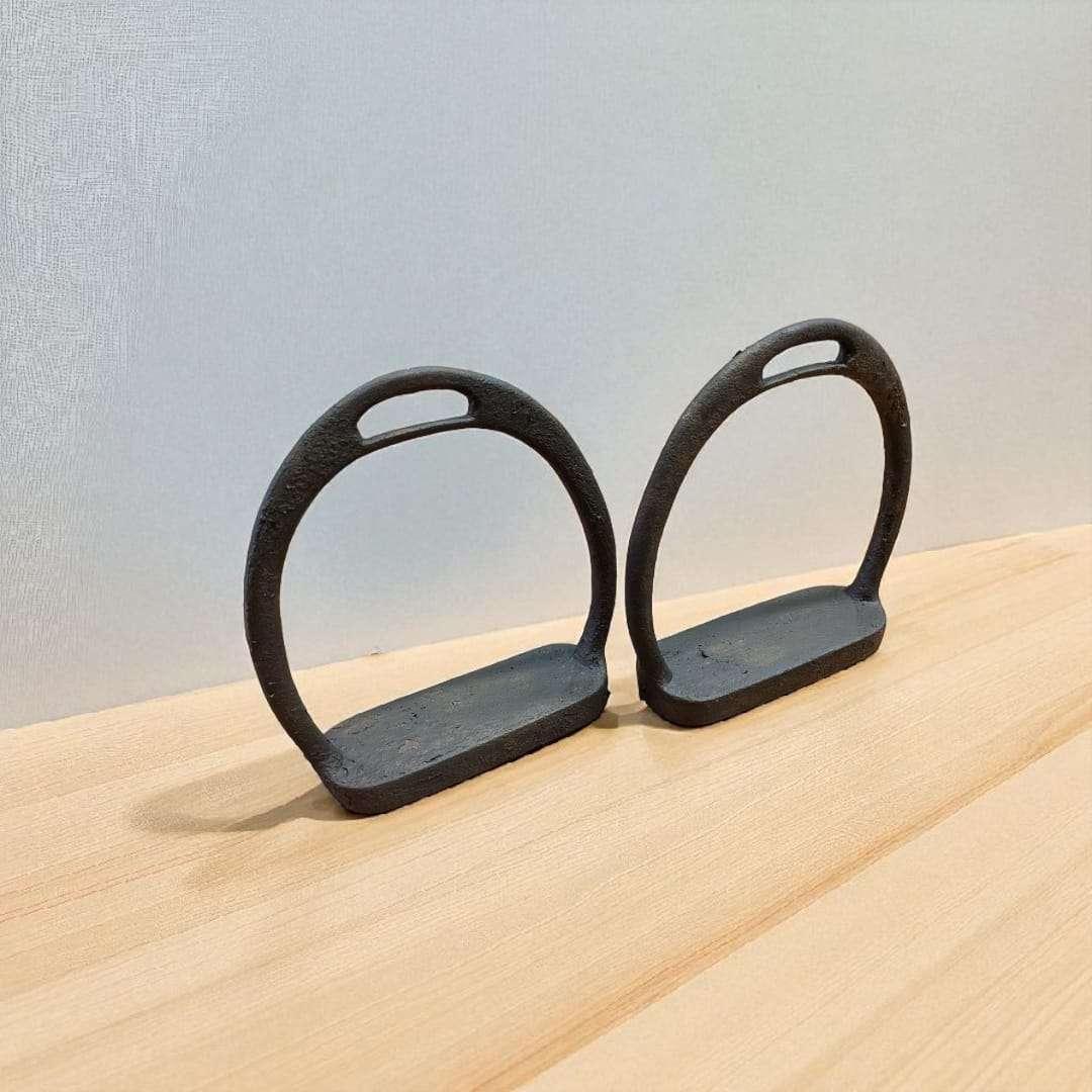 Par de estribos antiguos de forja sobre suelo de madera clara