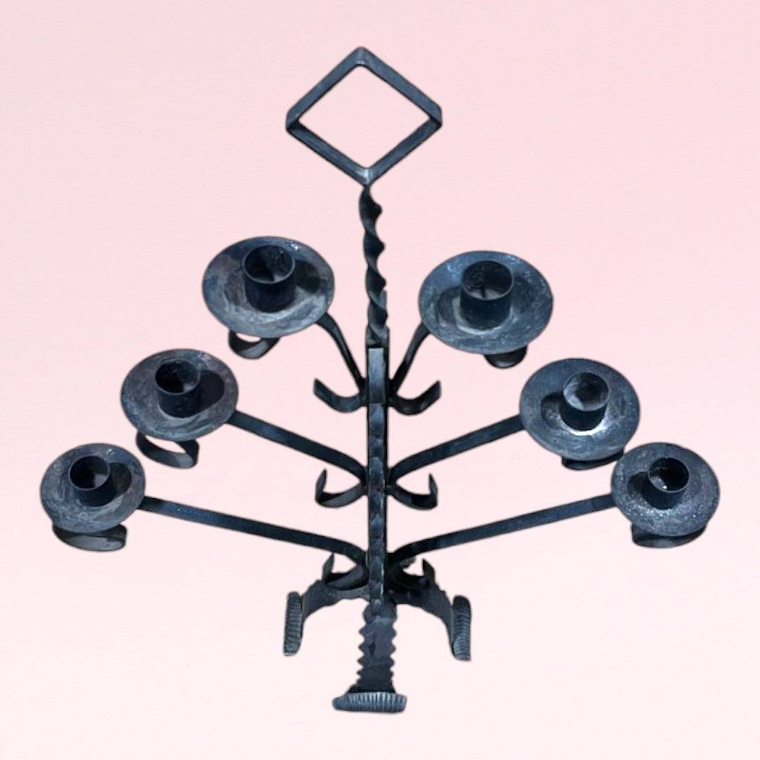 Candelabro antiguo de forja de 6 brazos con diseño simétrico y acabado rústico, ideal para decoración vintage en interiores elegantes.