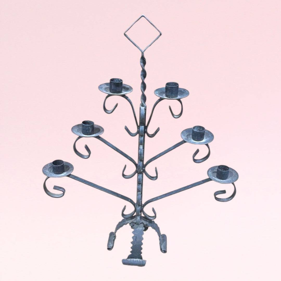 Candelabro antiguo de forja de 6 brazos con diseño simétrico y acabado rústico, ideal para decoración vintage en interiores elegantes.