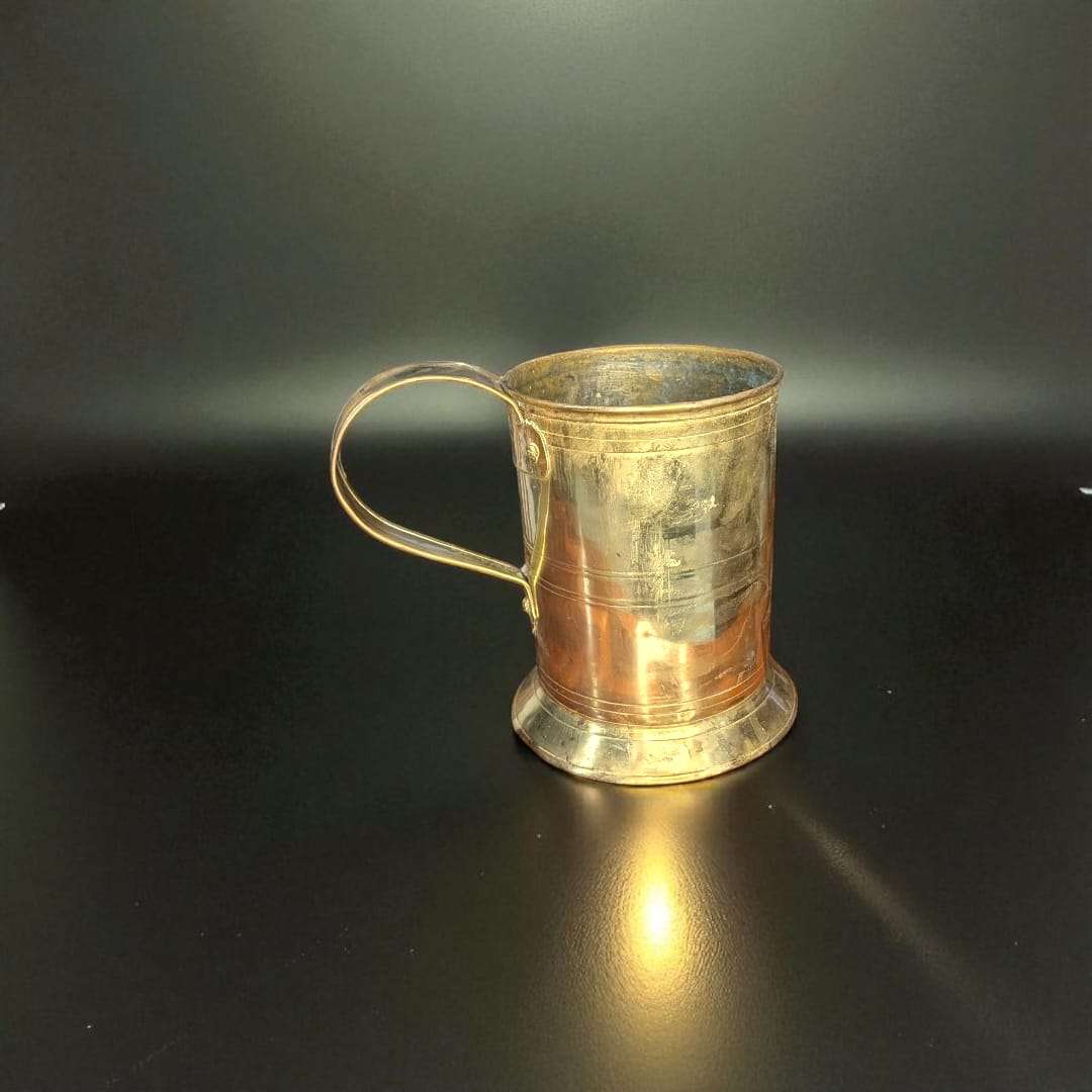 Jarra de Cerveza Alemana en metal vintage coleccionista sobre escritorio con libros antiguos. Decoración ideal para amantes de la cervecería clásica.