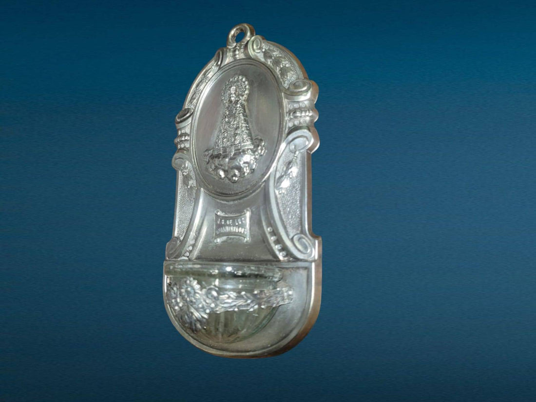 Benditera metal plateado Virgen de los Desamparados con diseño en relieve y detalles ornamentales, ideal para decoración religiosa en el hogar.