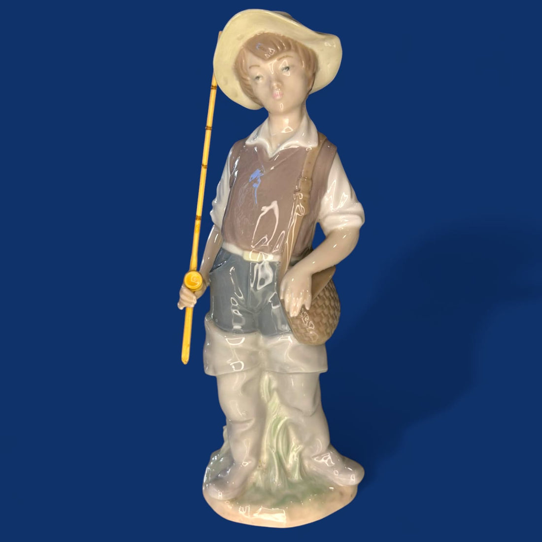 La encantadora figura “Fisher Boy” (Niño Pescador) de Lladró captura la inocencia y tranquilidad de la infancia con una delicada escena protagonizada por un joven pescador descansando junto a su caña.