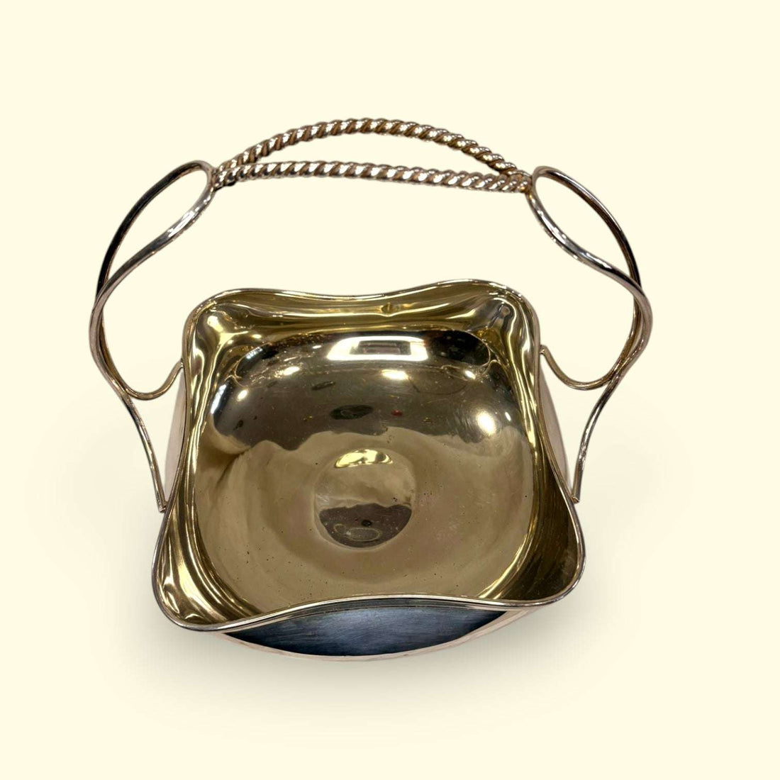 Este Centro de mesa de metal plateado es una pieza elegante, luminosa y muy versátil, diseñada con forma de cesta y asa superior para facilitar su transporte y colocación. 