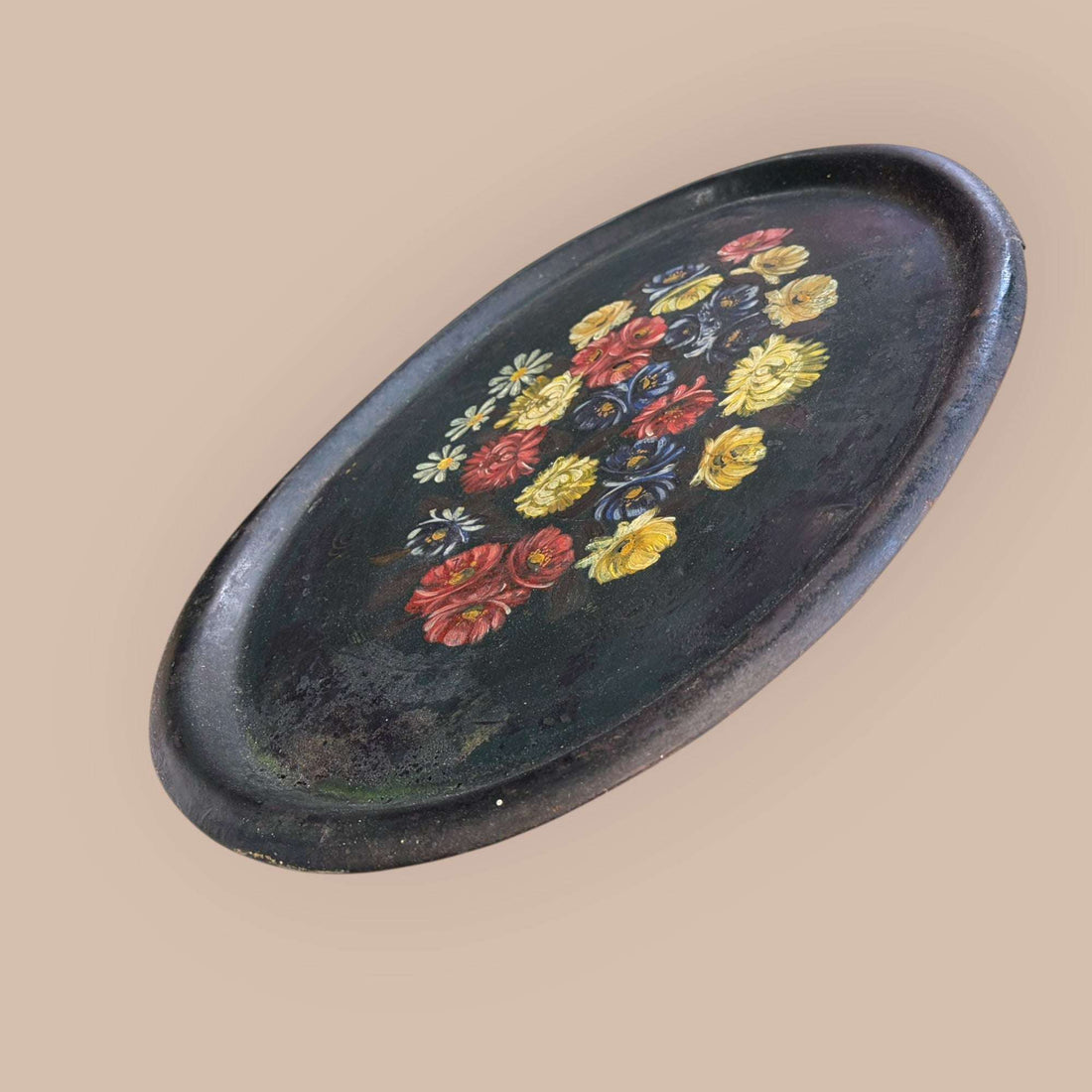 Esta Bandeja antigua de tole, realizada en metal pintado, es una pieza decorativa con gran personalidad visual.