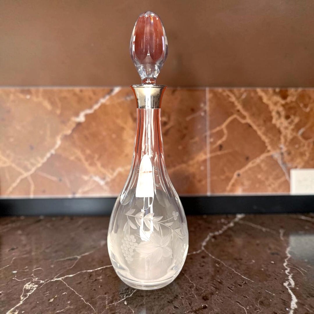 Este decantador de cristal con cuello de plata destaca por una silueta 