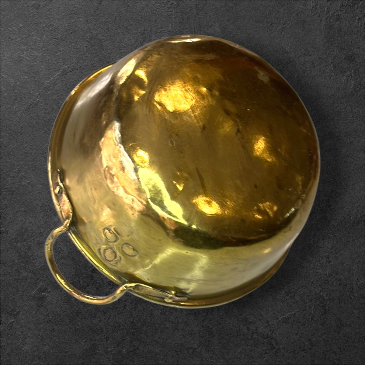 La superficie dorada no es completamente uniforme. Se observan pequeñas marcas, arañazos y cambios de tonalidad, especialmente en el interior.