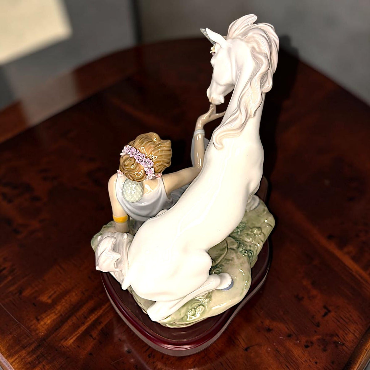  extiende una de sus manos hacia un unicornio situado a su lado.