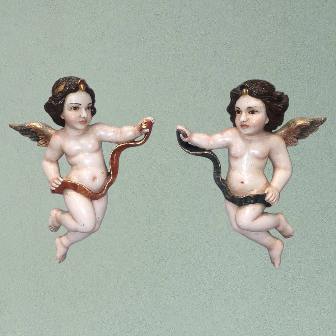 Vista frontal de la pareja de ángeles tallados en madera, mostrando sus detalles artesanales.