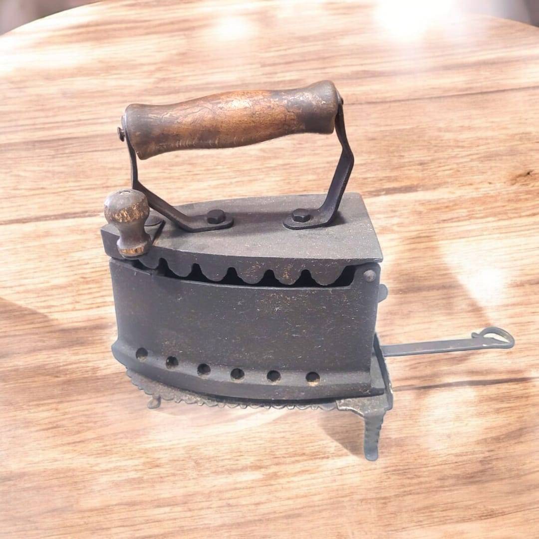 Descansa plancha hierro forjado antiguo con diseño curvo y detalles ornamentales, ideal para decoración vintage en hogar o colección.