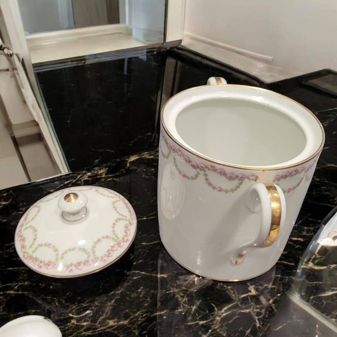 Azucarero de porcelana francesa con tapa y asas doradas, decorado con guirnaldas de rosas rosadas sobre fondo blanco. Ideal para decoración elegante.