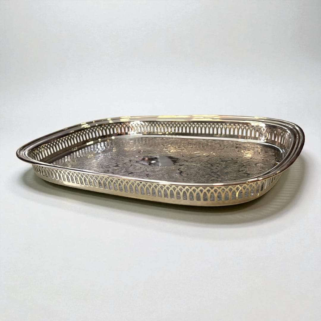 Bandeja de metal plateada grabada con bordes calados.