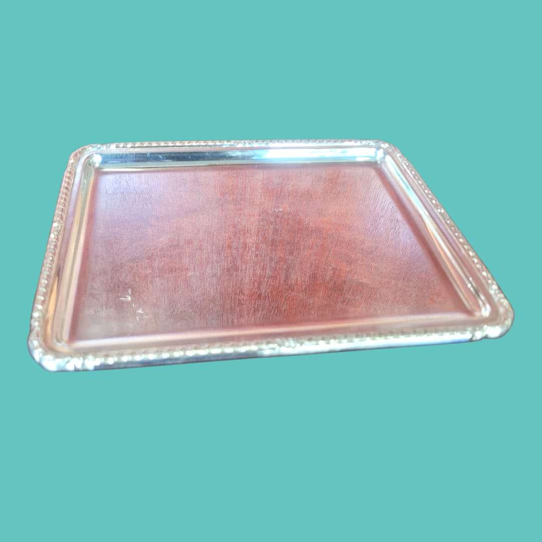 Bandeja de metal plateado con ornamentos elegantes y marco repujado clásico, ideal para decoración de interiores en estilo vintage.