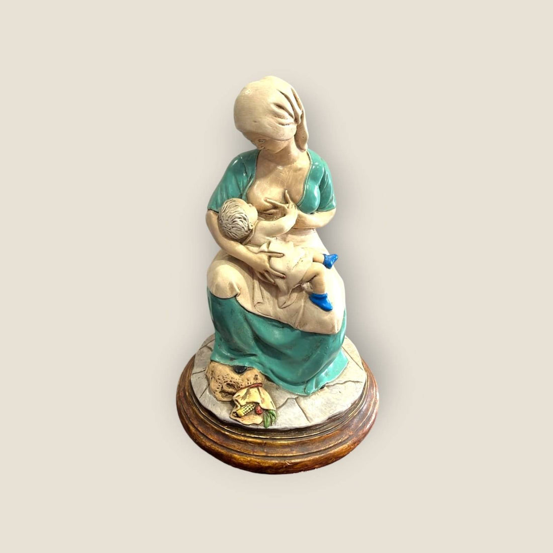 Figura maternidad amamantando en cerámica sobre base de madera, símbolo de amor natural y conexión para decoración del hogar.