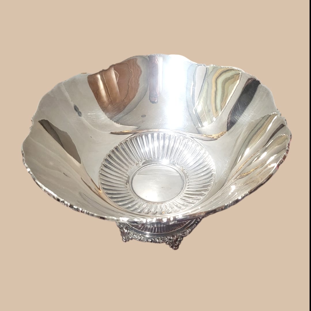 Centro de mesa de metal plateado con diseño elegante y bordes decorativos, ideal para decoración de interiores.