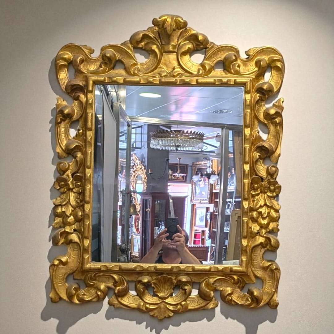 Espejo dorado isabelino del siglo XIX con talla en madera, marco ornamentado con penacho decorativo ideal para decoración clásica de interiores.