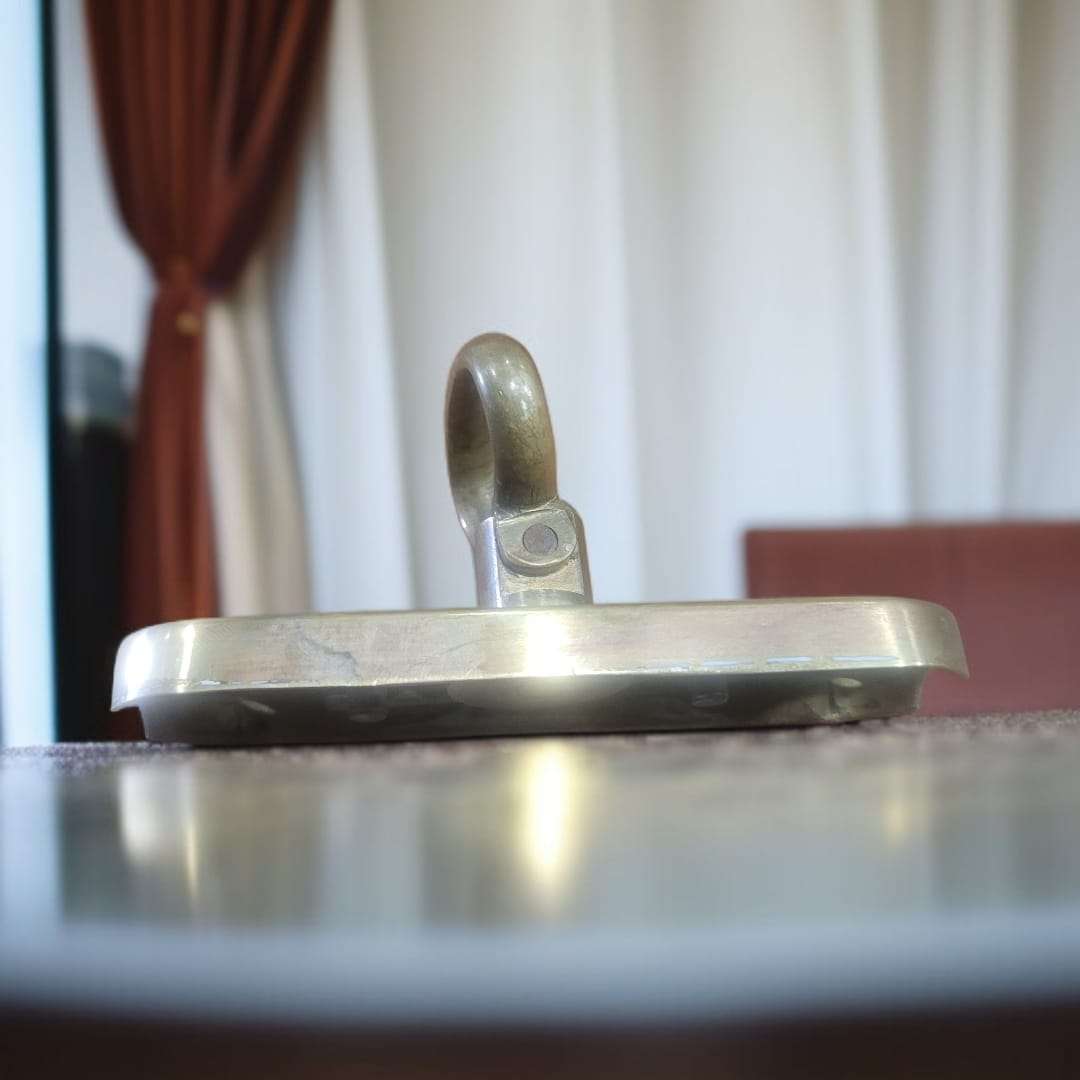 "Falleba antigua de metal dorado vista lateral sobre mesa"