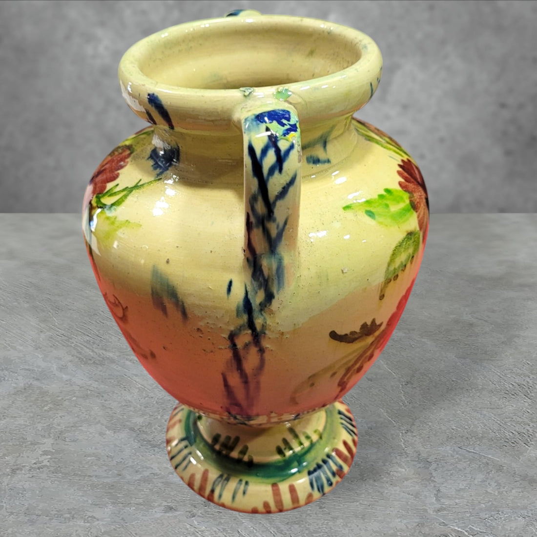 Ánfora de cerámica esmaltada pintada a mano con diseño floral en tonos cálidos. Elegante pieza artesanal ideal para la decoración del hogar.
