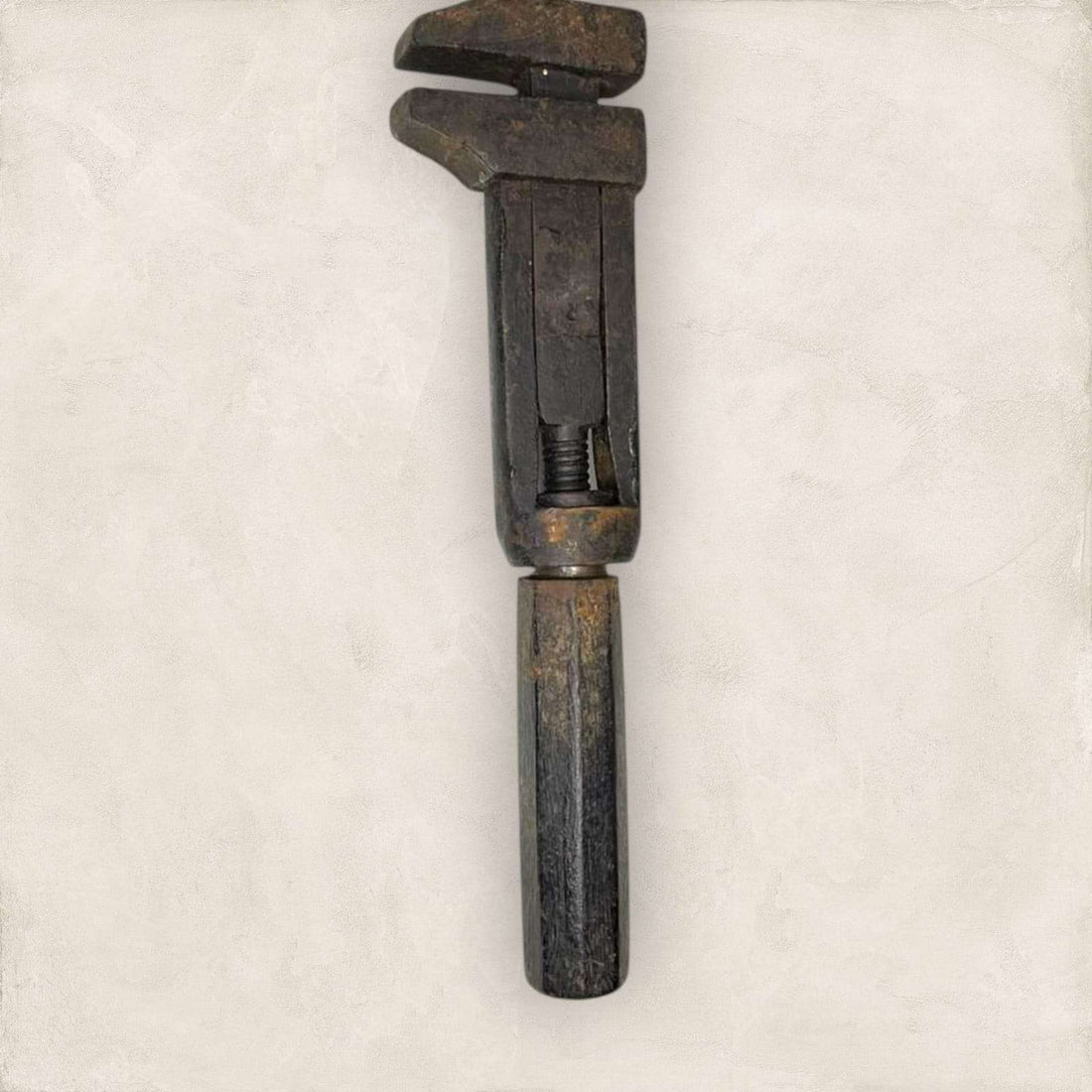 Llave inglesa antigua ajustable vista lateral con pátina metálica.