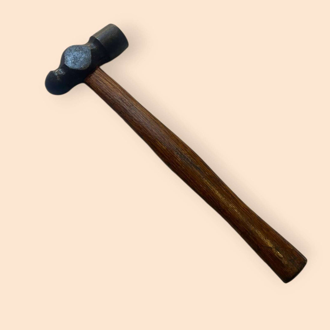 Martillo de bola visto en ángulo inclinado sobre fondo beige.