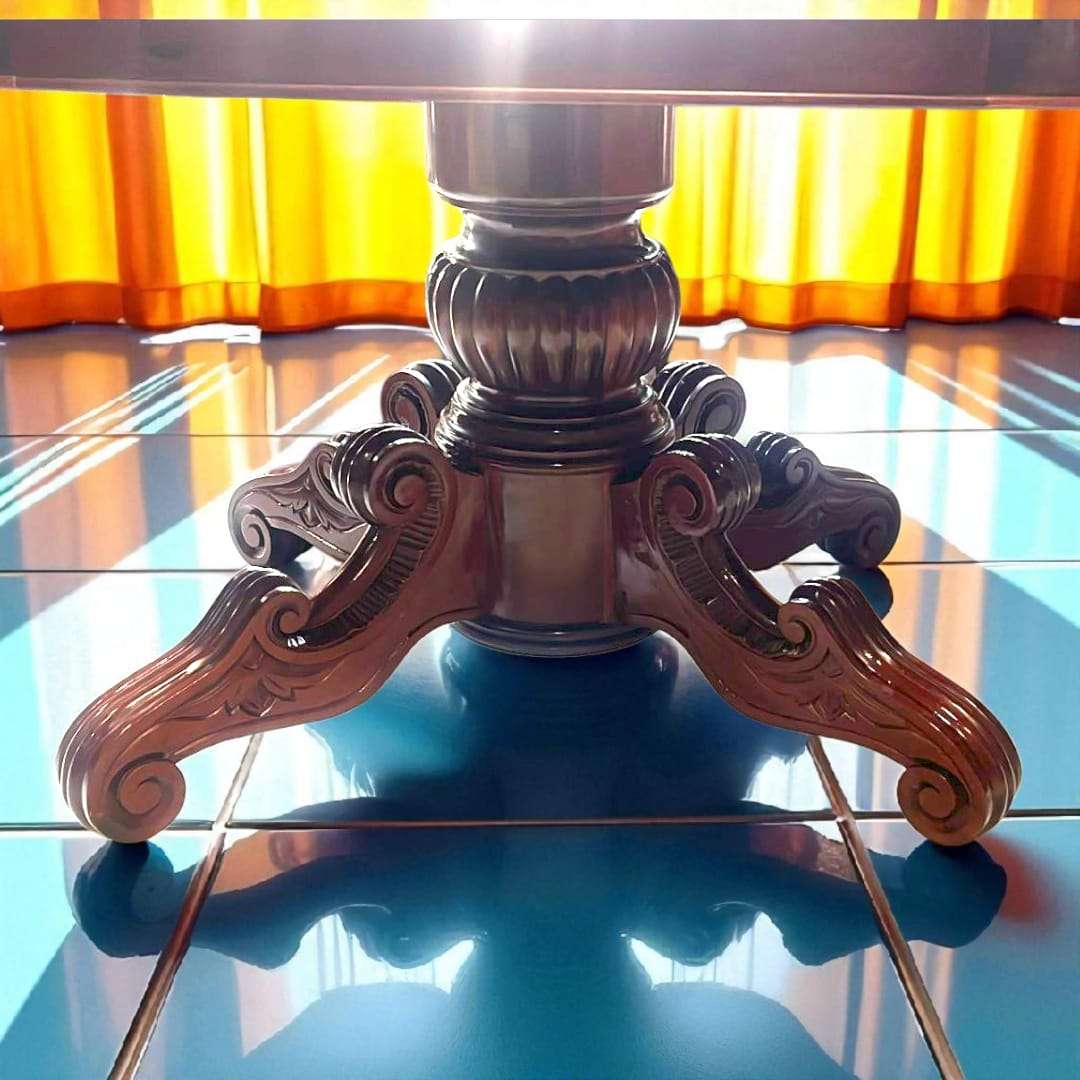 Mesa comedor de caoba antigua con patas talladas a mano, superficie ovalada brillante y acabado clásico, ideal para decoración elegante.