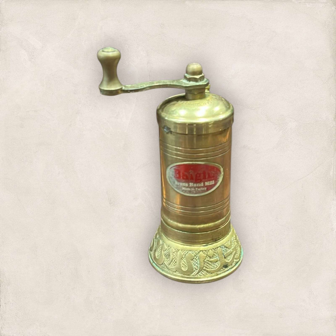 Molinillo de pimienta manual dorado de metal tallado estilo turco con diseño artesanal y manivela superior, ideal para cocina elegante.