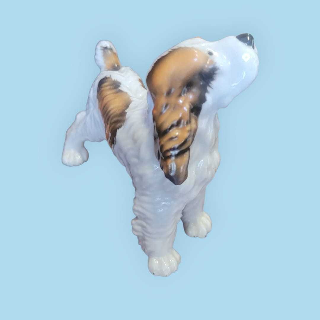 Figura coleccionista de perro Cocker de porcelana alemana Trébol años 50, esmaltada con detalles realistas en blanco y marrón.