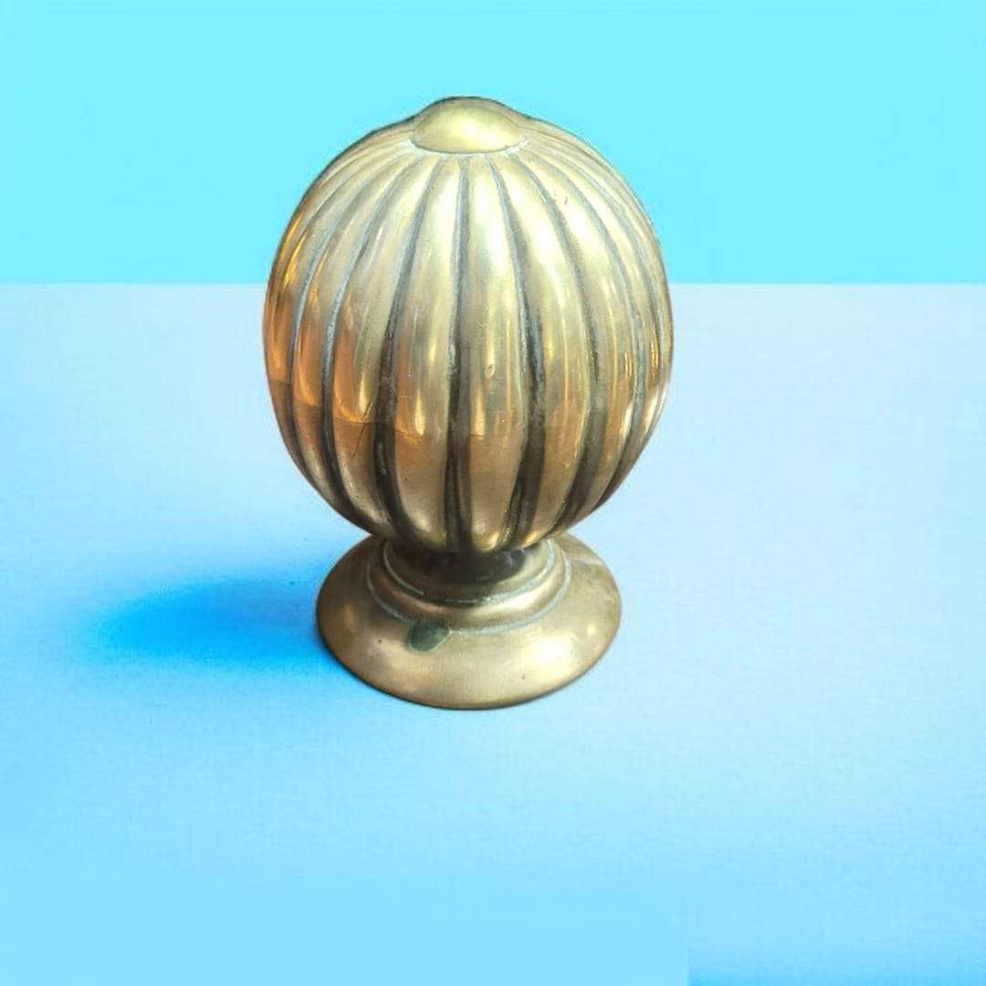 Pomo o remate decorativo de bronce sobre madera barnizada