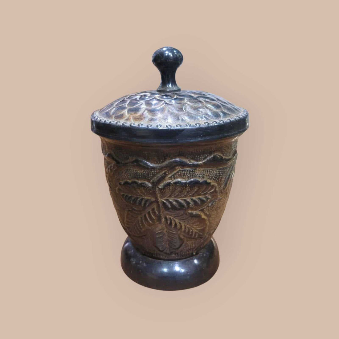 Tibor de metal con relieves vegetales y tapa decorada con patrón floral, ideal para decoración de interiores en estilo rústico o vintage.