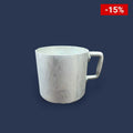 Vista frontal de la taza de aluminio con mango ergonómico sobre una mesa de madera.​

