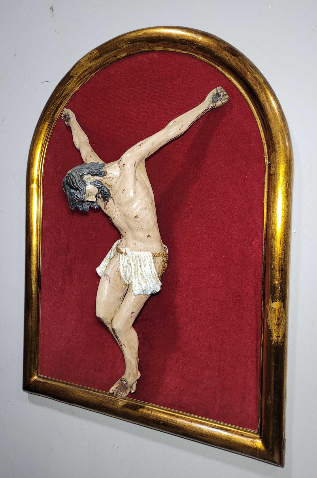 Cristo en terracota sin cruz sobre fondo rojo y marco dorado, ideal para decoración espiritual del hogar. Elegancia y devoción en cada detalle.